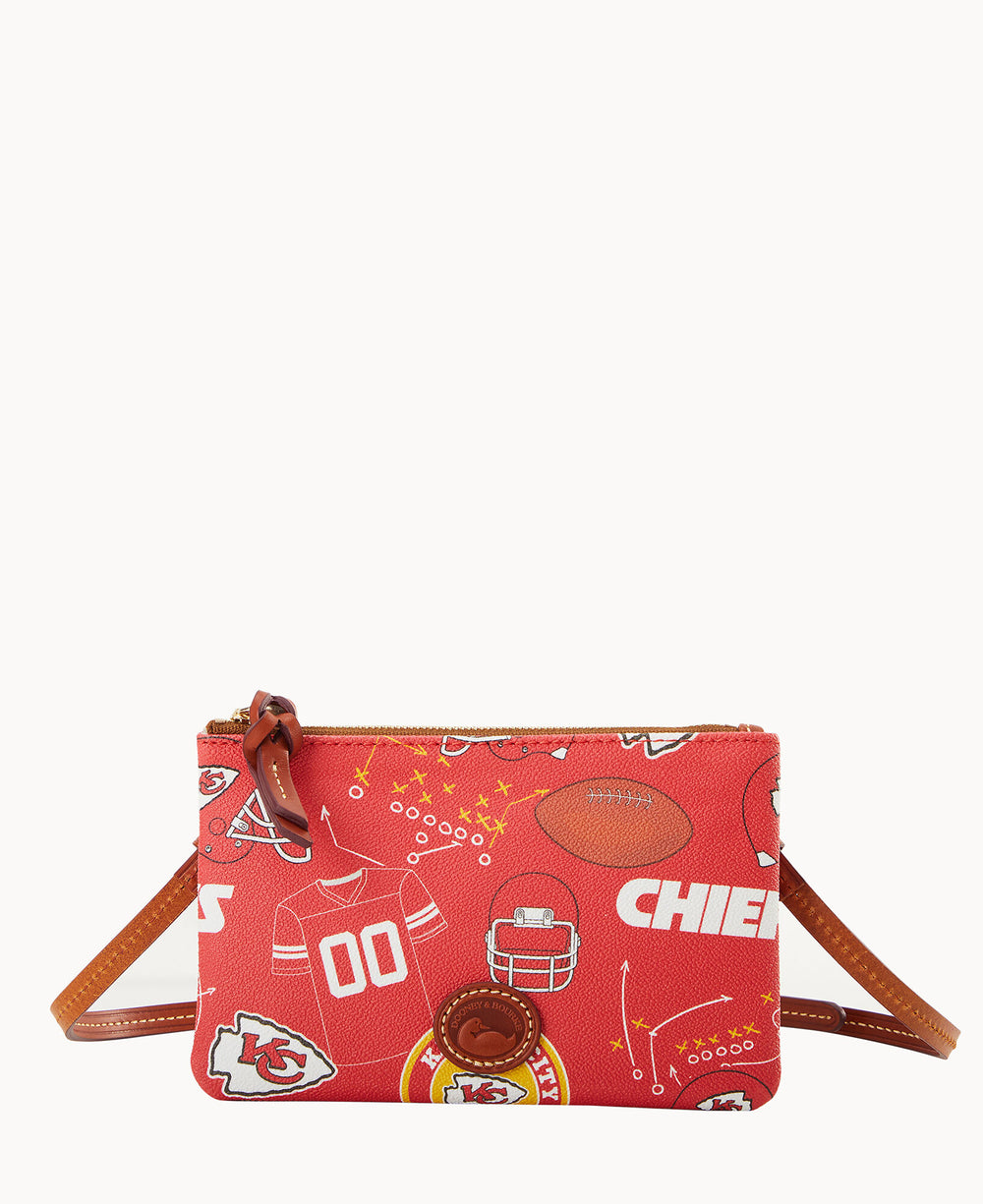 A small red crossbody bag featuring Kansas City Chiefs football-themed graphics, including jerseys, helmets, footballs, and the Chiefs logo. The bag has a brown leather strap and a zippered top.