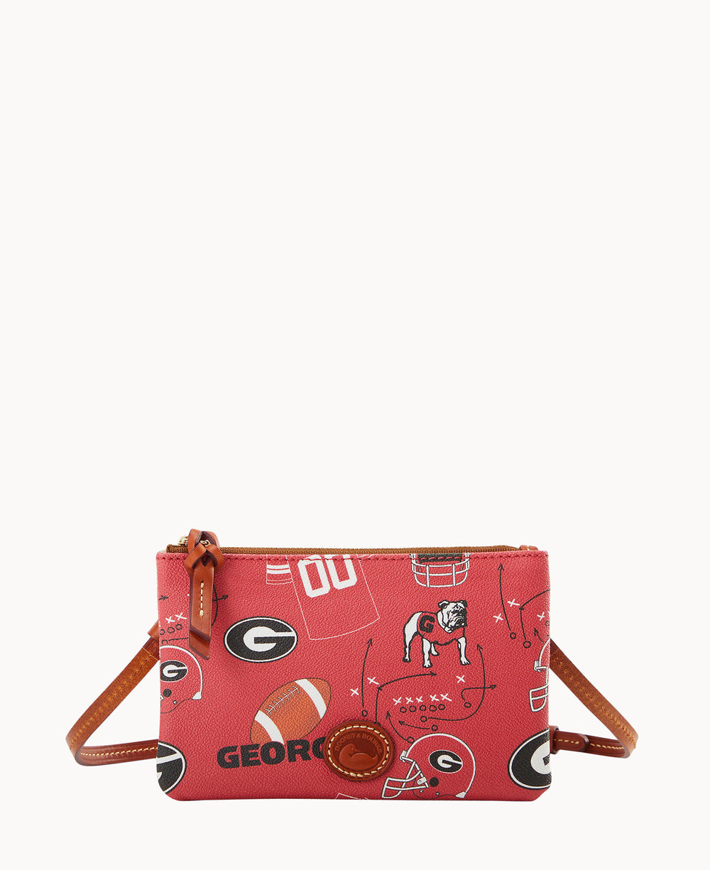 A small red crossbody bag with brown strap featuring Georgia Bulldogs graphics, including footballs, helmets, the team logo, a bulldog, and play diagrams. The bag has a zippered top and a circular leather accent on the front.