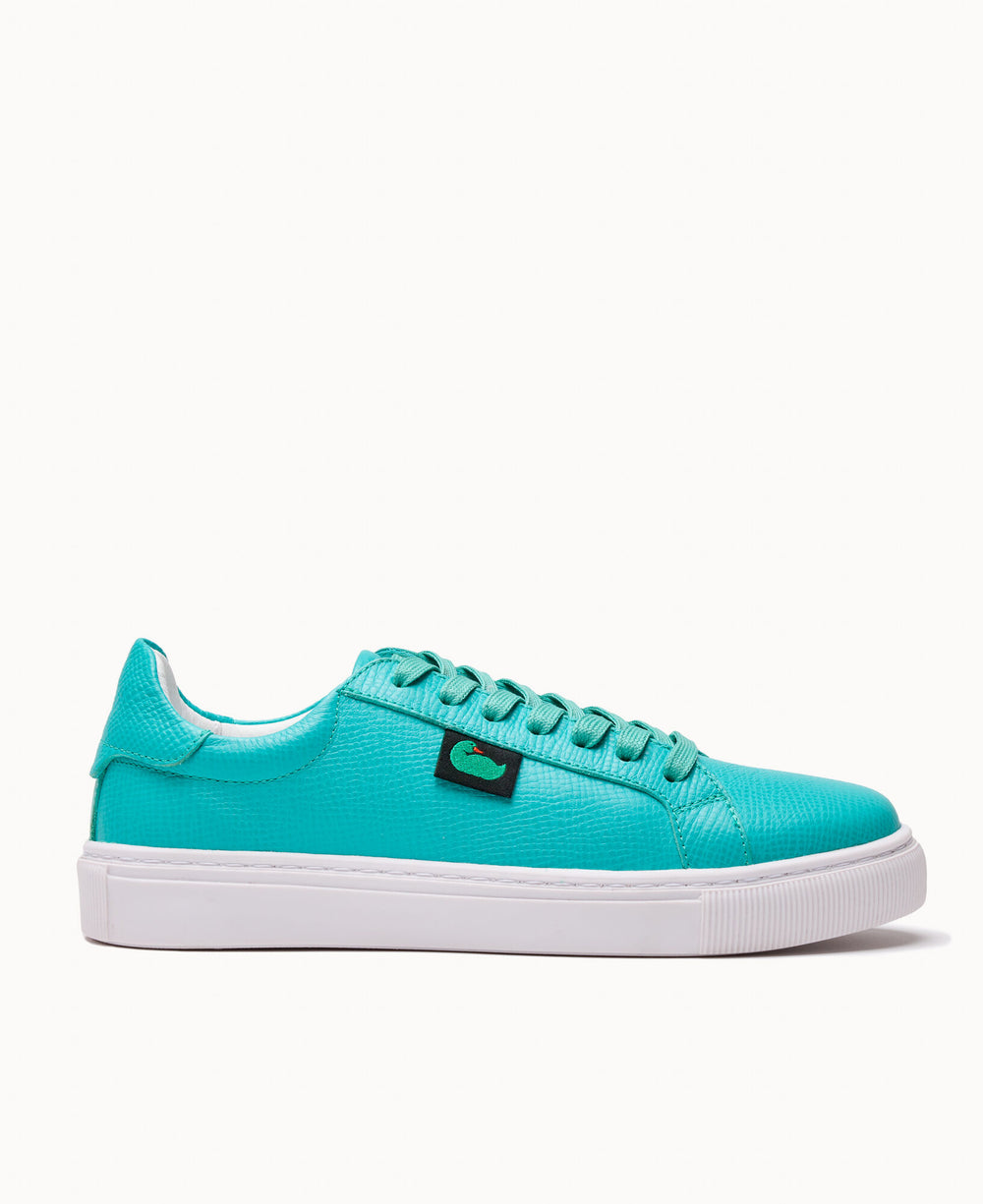 Bright turquoise low-top sneakers featuring embossed leather upper, black logo patch, and chunky white sole
