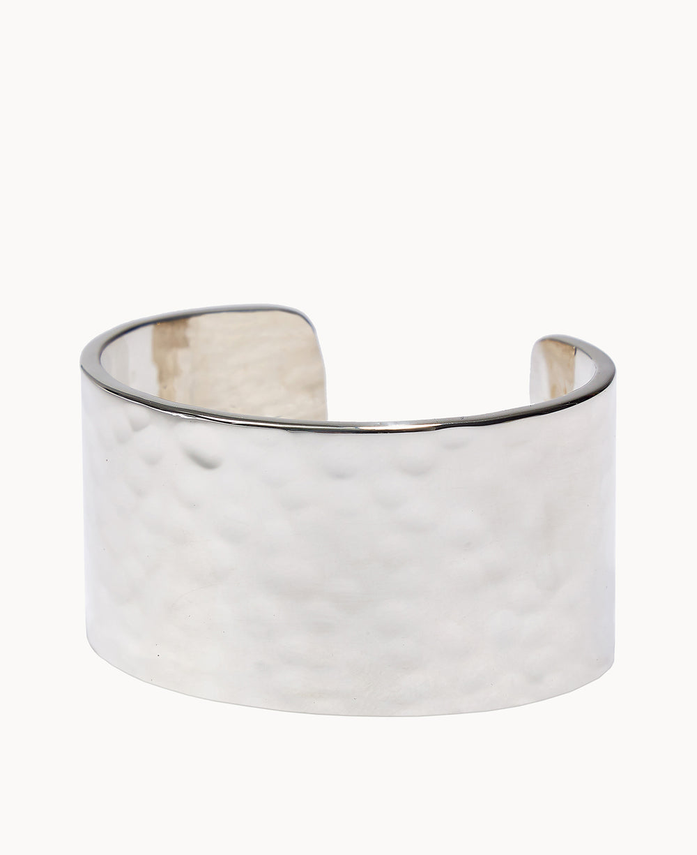 A wide, open-ended silver cuff bracelet with a polished, hammered texture.