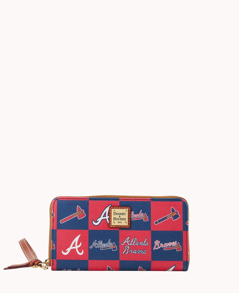A red and blue checkered wallet featuring Atlanta Braves logos, tomahawks, and Atlanta Braves text, with a leather zipper pull and a Dooney & Bourke label on the front.