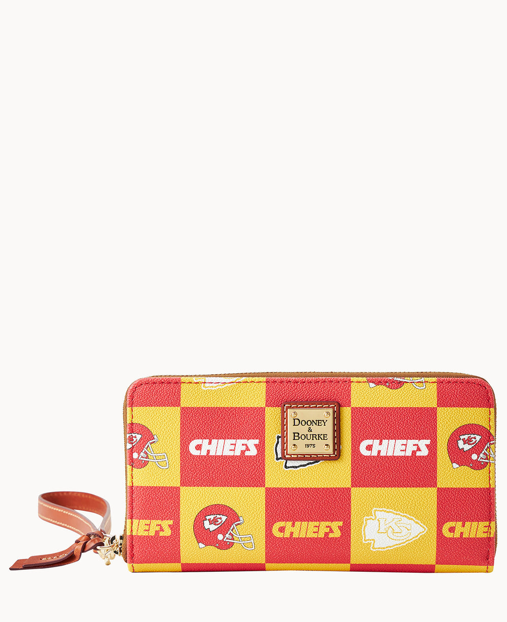 A rectangular wallet with a red and yellow checkered pattern featuring Kansas City Chiefs logos and the word CHIEFS, with a brown leather wrist strap and a Dooney & Bourke label on the front.