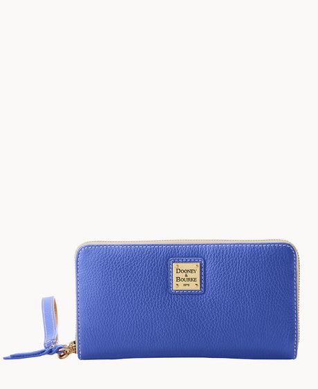 A blue leather zip-around wallet with a gold Dooney & Bourke logo plate on the front and a matching zipper pull, shown against a white background.