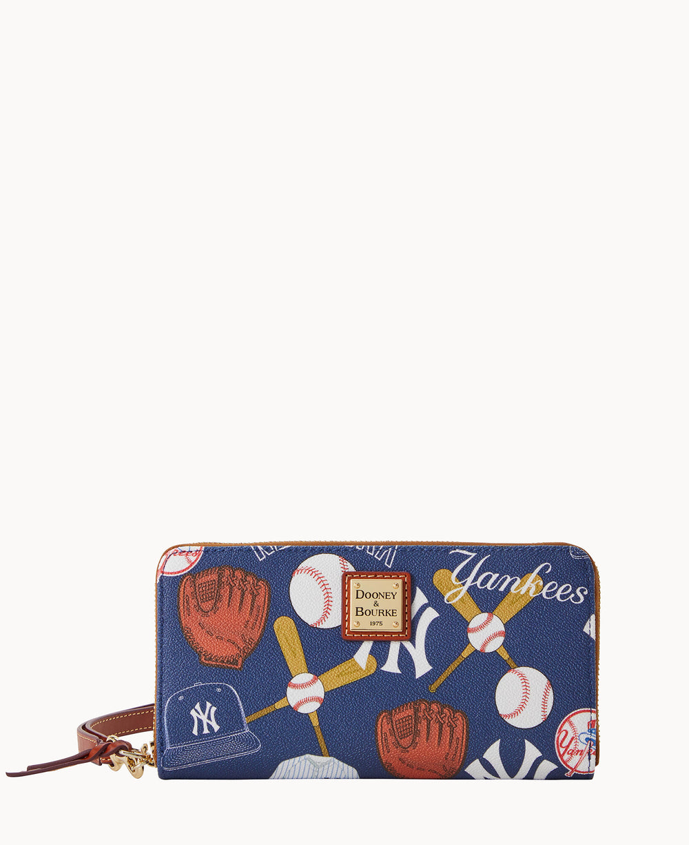 A navy wallet with a zipper and wrist strap, decorated with baseball-themed illustrations including gloves, bats, balls, caps, and the word Yankees. A Dooney & Bourke logo patch is on the front.