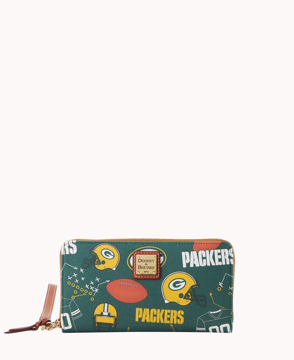 A green zip-around wallet with Green Bay Packers logos, football helmets, and football graphics, featuring a Dooney & Bourke label on the front and a tan leather zipper pull.
