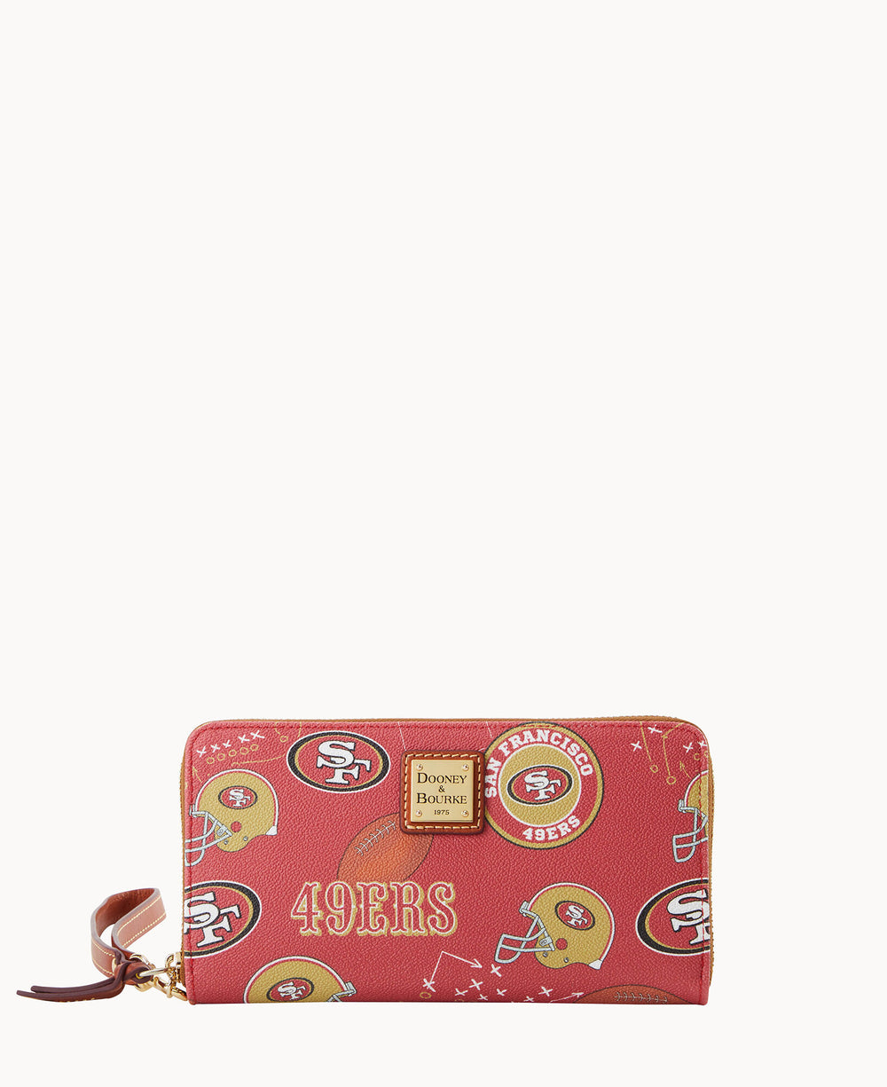 A red wallet with San Francisco 49ers logos and football graphics, featuring a gold Dooney & Bourke label on the front and a brown leather wrist strap attached to the zipper.