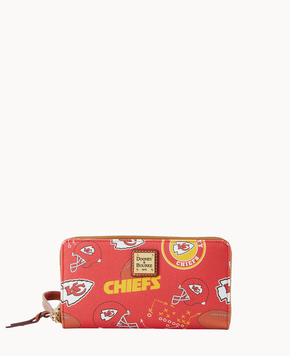 A red Dooney & Bourke zip-around wallet featuring the Kansas City Chiefs logo, football helmets, and the word CHIEFS in bold yellow lettering, with a brown leather wrist strap.