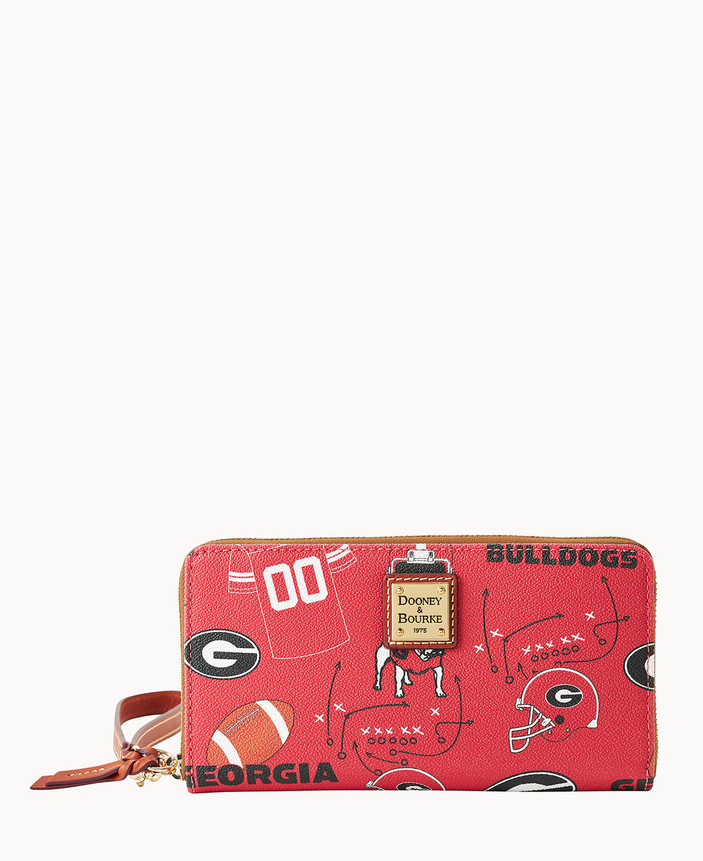 A red Dooney & Bourke zip wallet featuring University of Georgia Bulldogs-themed graphics, including footballs, helmets, jerseys, and the â€œGEORGIAâ€ and â€œBULLDOGSâ€ text, with a wrist strap attached.