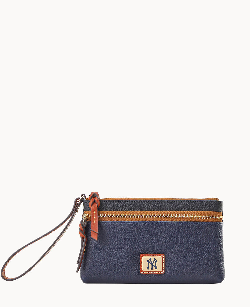A navy blue wristlet pouch with brown trim, a zippered top, a leather strap, and a logo patch featuring the letters â€œNYâ€ in dark blue on a beige background.