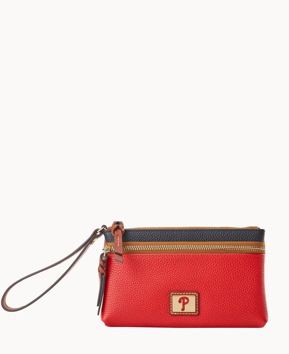 A small red zippered wristlet pouch with a brown strap, gold zipper, black trim, and a gold square emblem featuring a red script letter P on the front.