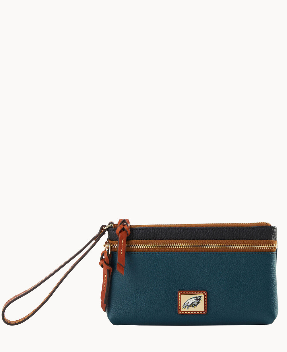 A teal leather wristlet with brown trim, a zipper closure, and a small rectangular patch featuring a stylized eagle logo on the front. The wrist strap is attached to the zipper.