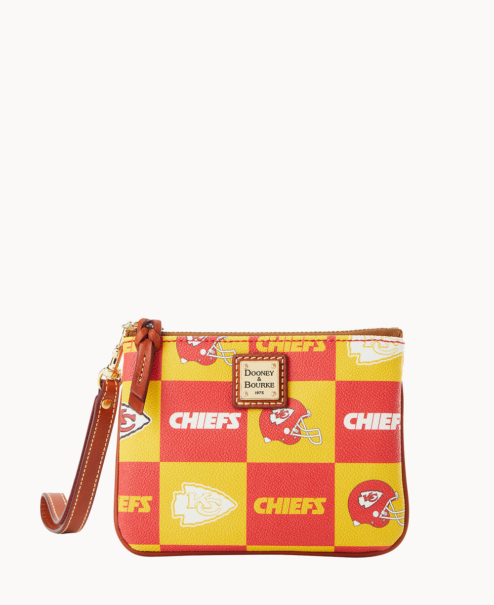 A small wristlet pouch features a red and yellow checkered pattern with Kansas City Chiefs logos and helmets, and a brown leather strap and trim. A Dooney & Bourke label is on the front.