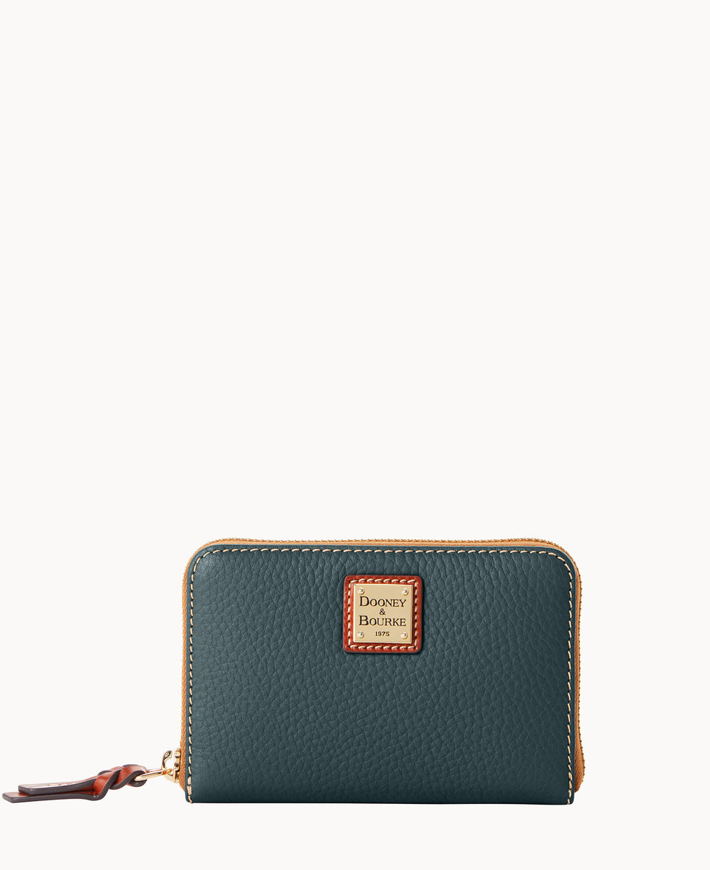 A dark green textured leather wallet with a gold zipper, brown leather pull tab, and a square Dooney & Bourke logo patch on the front, placed against a plain white background.