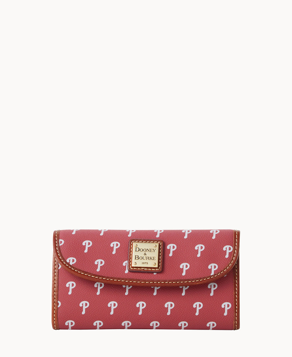 A red Dooney & Bourke wallet patterned with white P logos, featuring brown edging and a metal logo plate on the front.