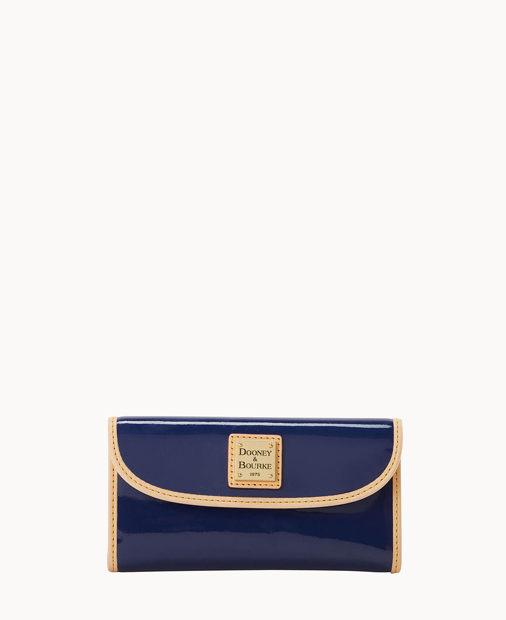 A navy blue patent leather wallet with tan trim and a gold Dooney & Bourke logo plaque on the front, displayed against a white background.