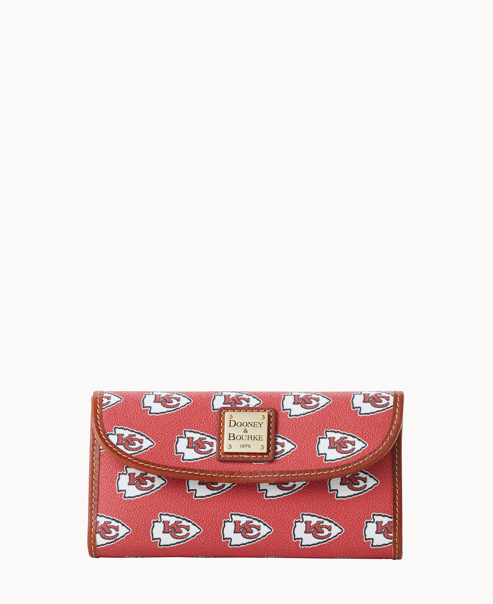 Red wallet with brown trim, featuring repeated Kansas City Chiefs logos and a gold Dooney & Bourke logo plate on the front.