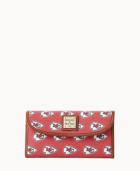 Red wallet with brown trim, featuring repeated Kansas City Chiefs logos and a gold Dooney & Bourke logo plate on the front.